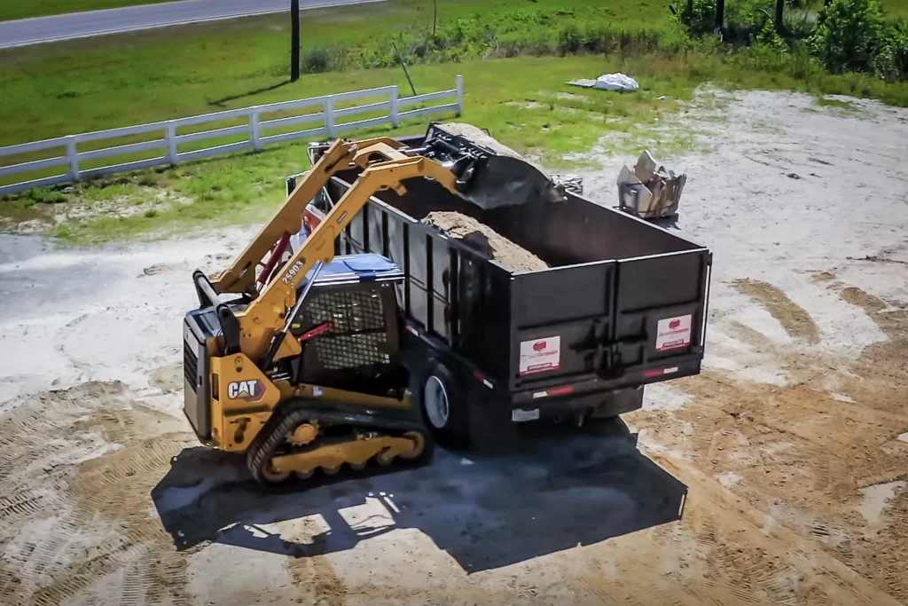 compact track loader for dirt work loading a truck while grading